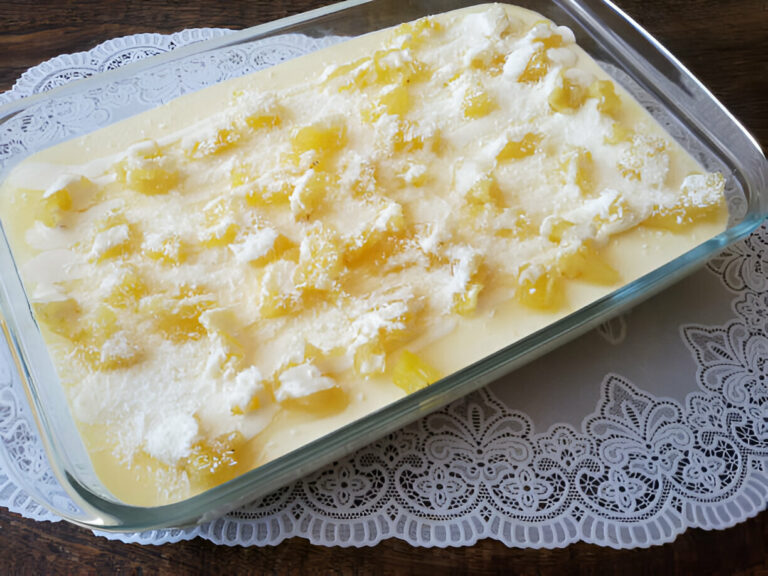 A delicious dessert in a glass dish topped with pineapple pieces and shredded coconut.