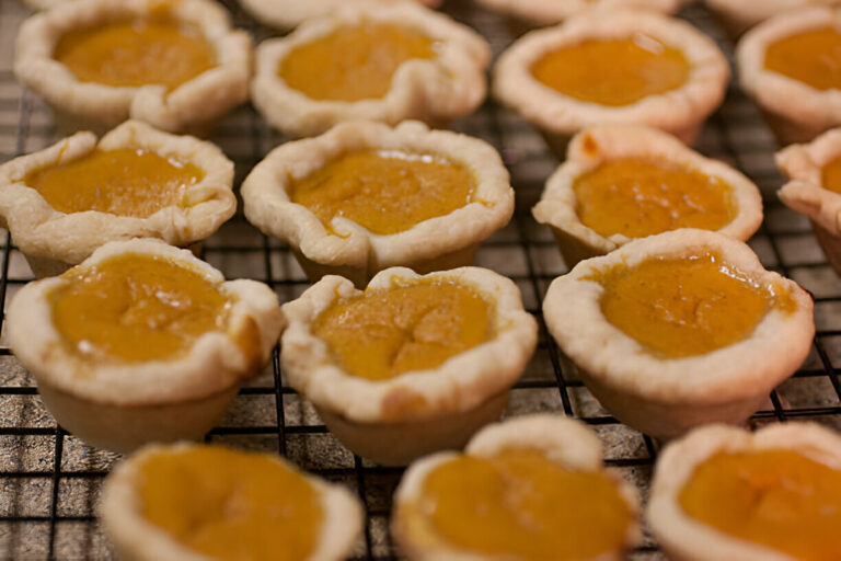 A close-up view of several mini pumpkin pies cooling on a wire rack.