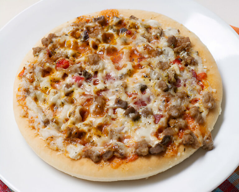 A delicious pizza topped with cheese, ground meat, and diced vegetables served on a white plate.