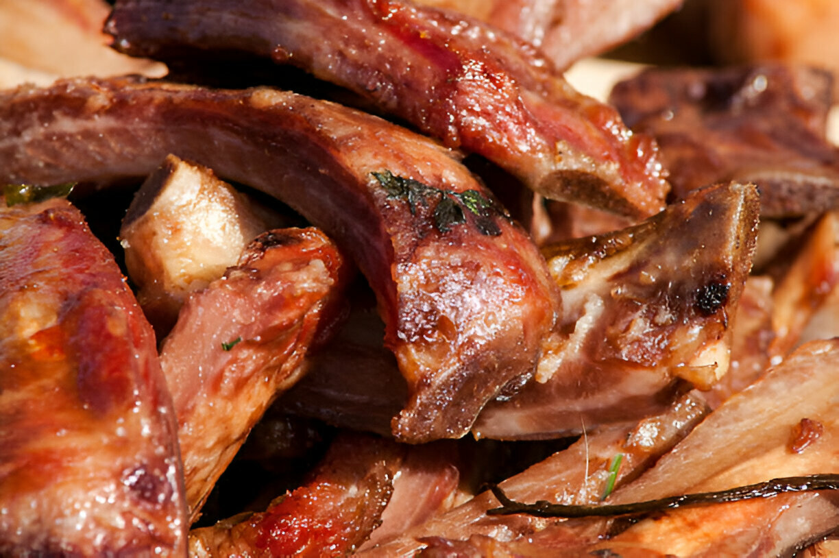 Close-up of succulent cooked ribs garnished with herbs.