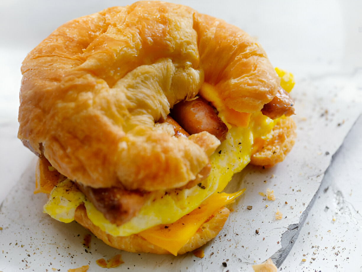 A delicious croissant sandwich filled with scrambled eggs, cheese, and sausage.