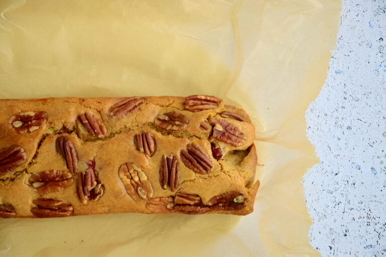 A loaf of baked bread with pecans, resting on parchment paper