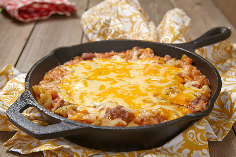 A delicious cheesy casserole in a cast iron skillet, featuring pasta, ground meat, and melted cheese on top.