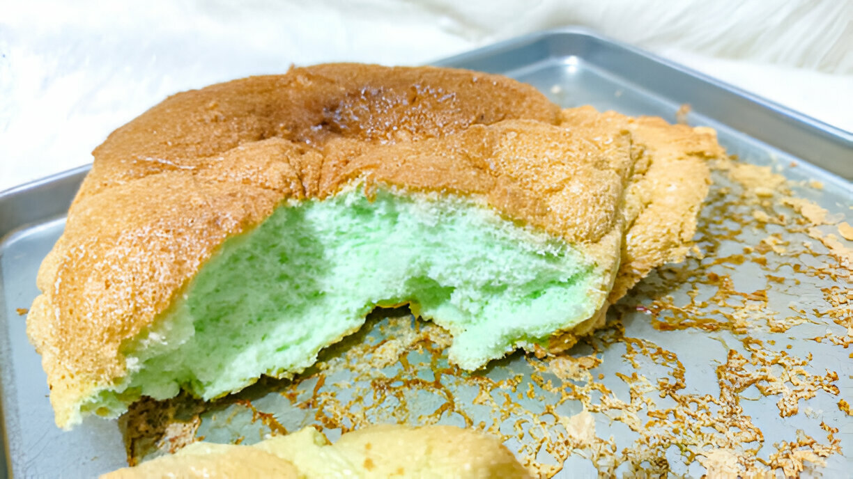 A partially eaten fluffy green cake on a baking tray