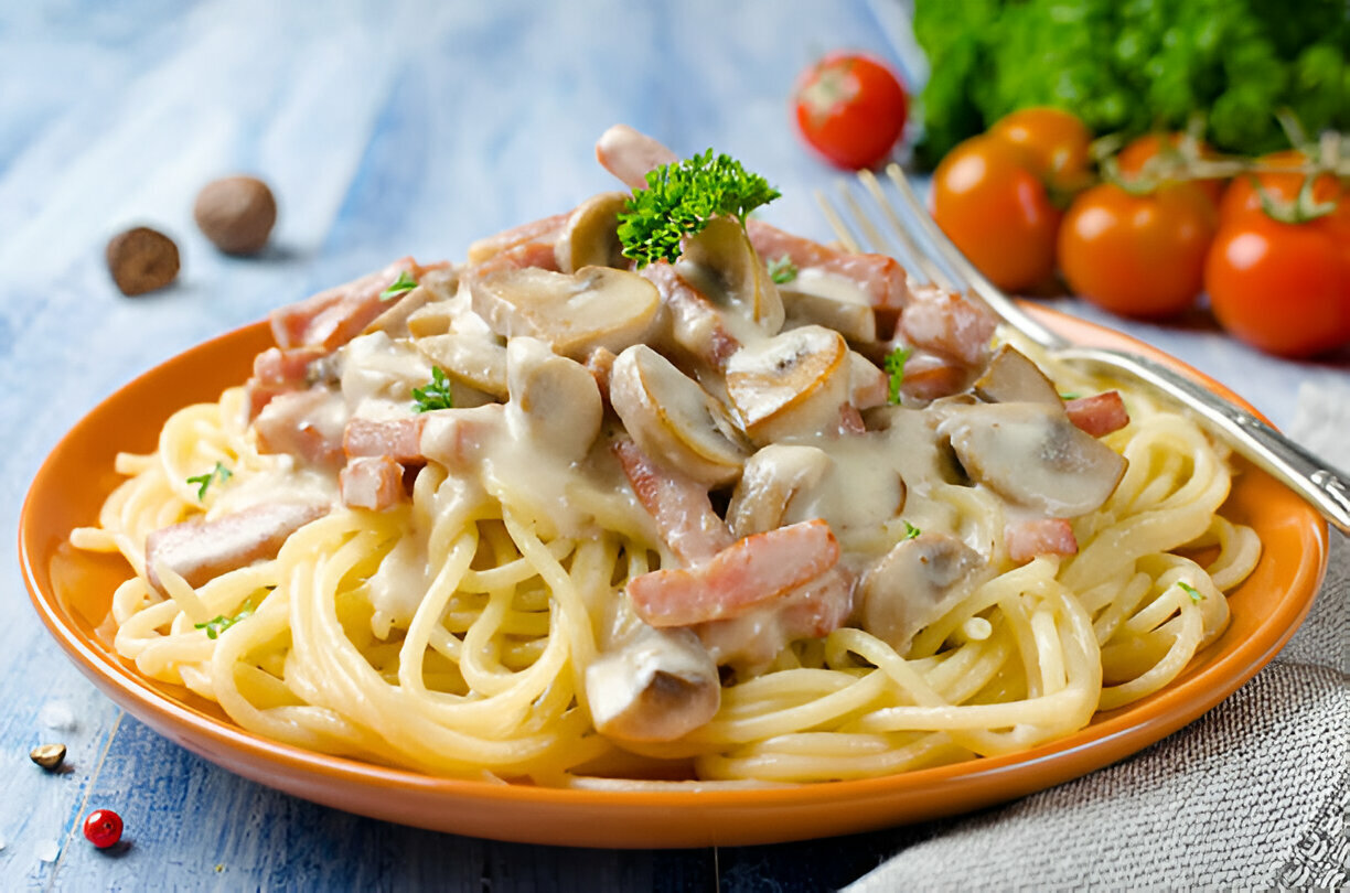 A plate of spaghetti topped with creamy mushroom and ham sauce, garnished with parsley.