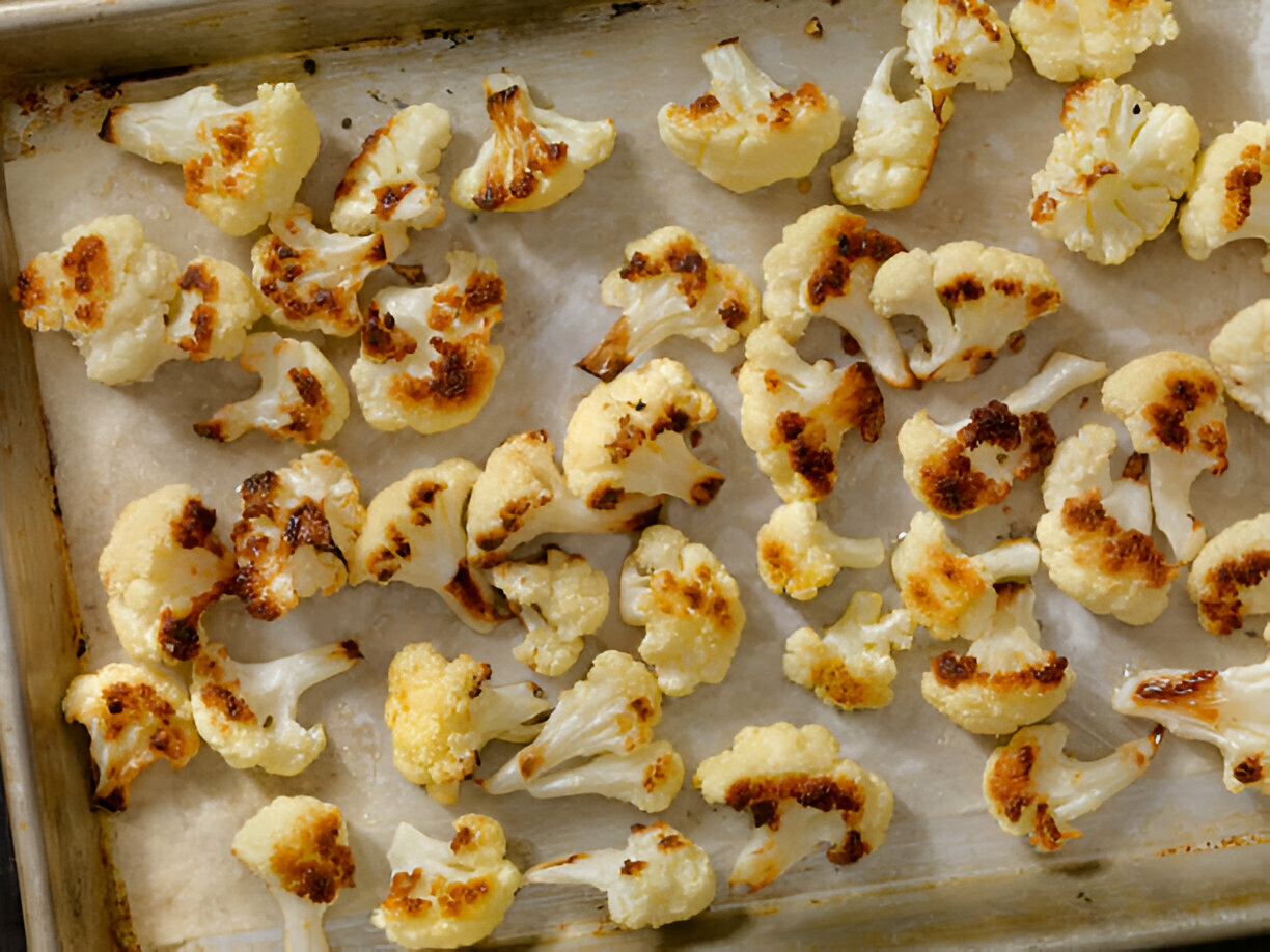 Roasted cauliflower florets on a baking sheet with a golden-brown surface.