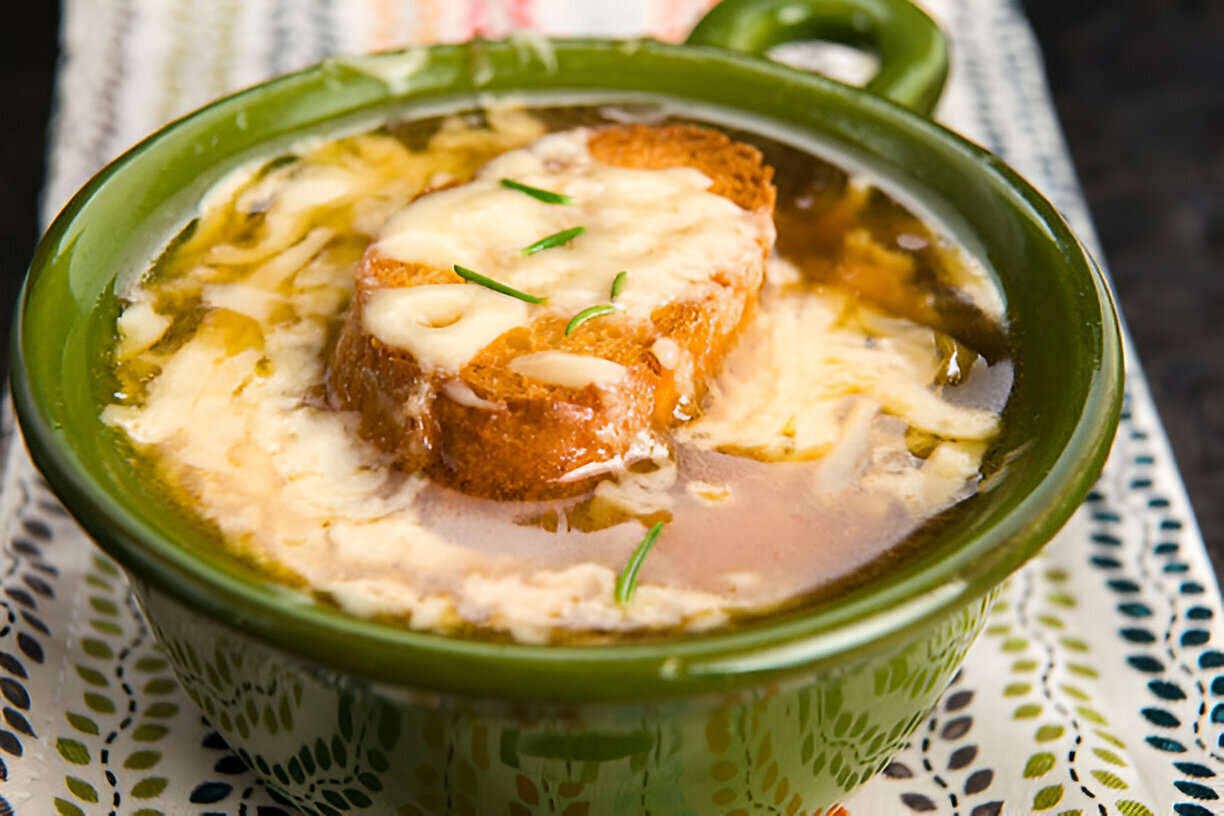 A bowl of French onion soup with melted cheese and toasted bread on top.