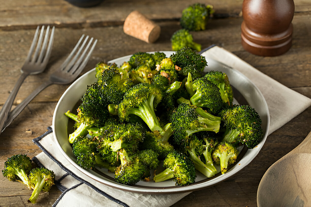 A plate of roasted broccoli on a wooden table