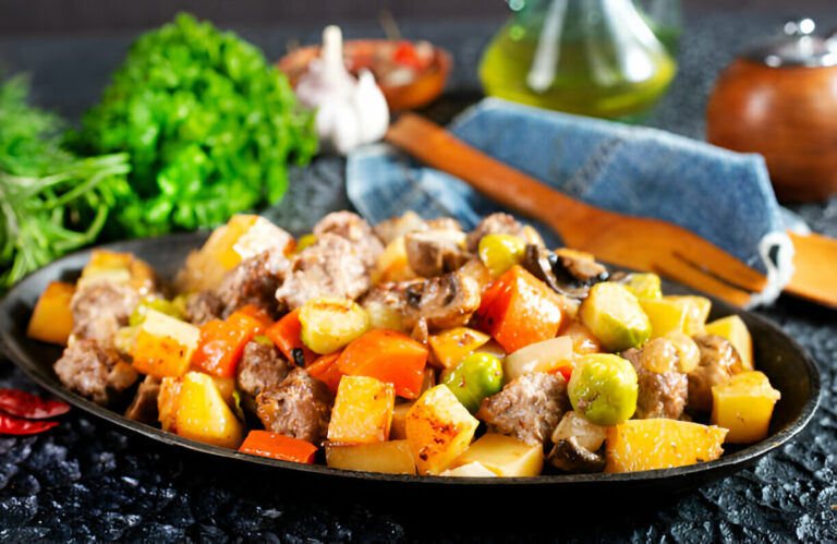 A colorful dish featuring mixed vegetables and meat served in a black dish.