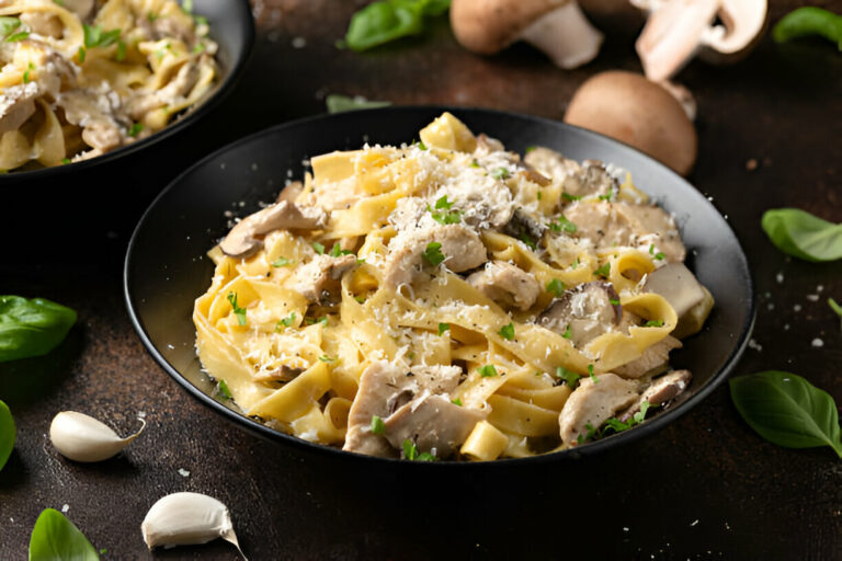 A bowl of creamy pasta with mushrooms, garnished with parsley and grated cheese.