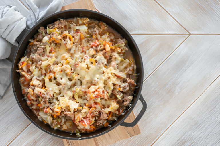 A skillet filled with a cheesy mixture of ground beef, vegetables, and melted cheese.