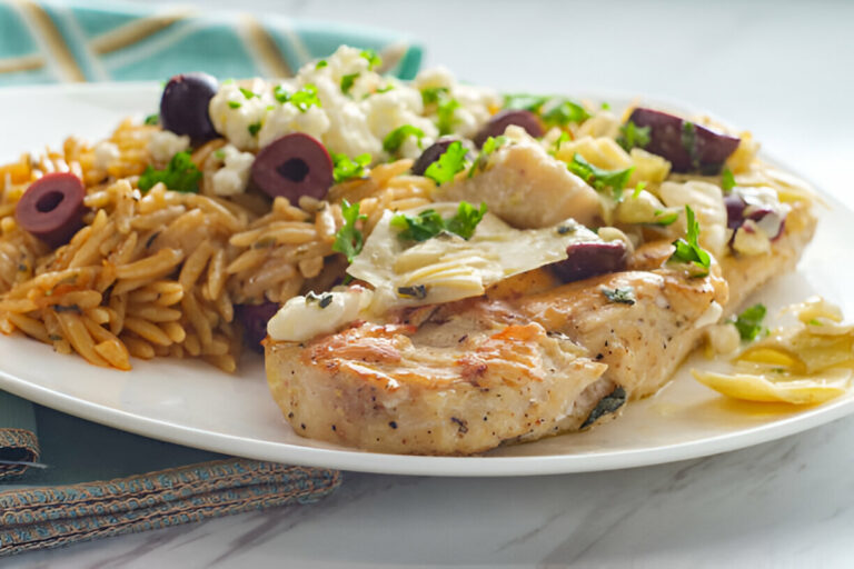 A delicious plate of grilled chicken served with orzo pasta and vegetables topped with herbs.