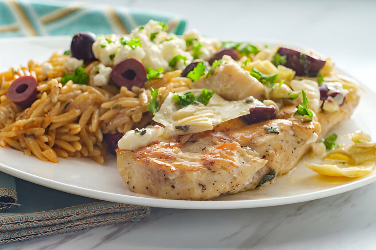 A delicious plate of grilled chicken served with orzo pasta and vegetables topped with herbs.