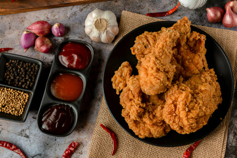 A plate of crispy fried chicken served with various sauces and spices