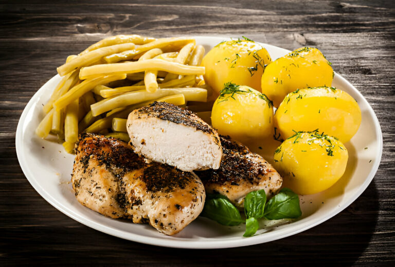 A plated meal with chicken, green beans, and boiled potatoes garnished with herbs.