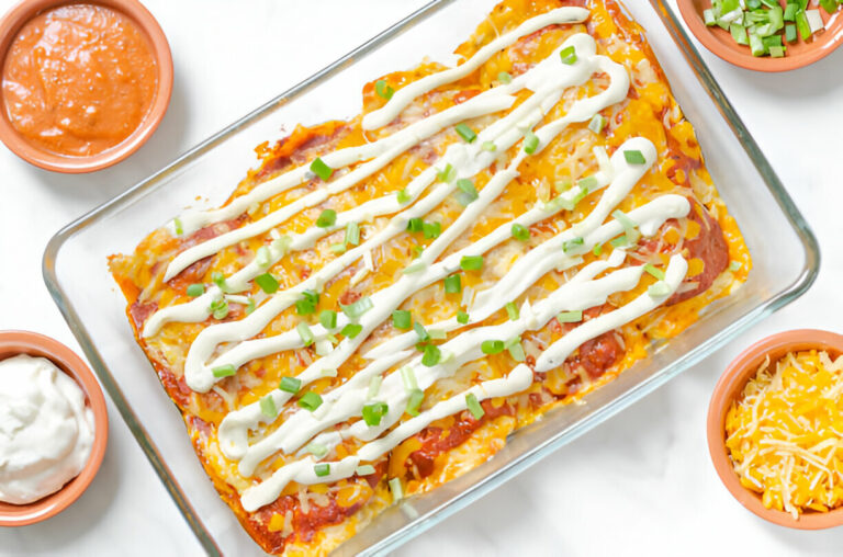 A delicious casserole dish of enchiladas topped with cheese and green onions, surrounded by small bowls of sauce and shredded cheese.