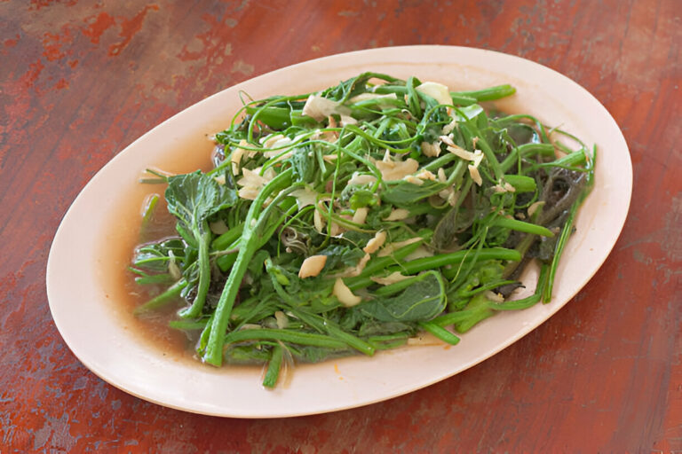 A plate of green vegetables sautéed with garlic on a wooden table.