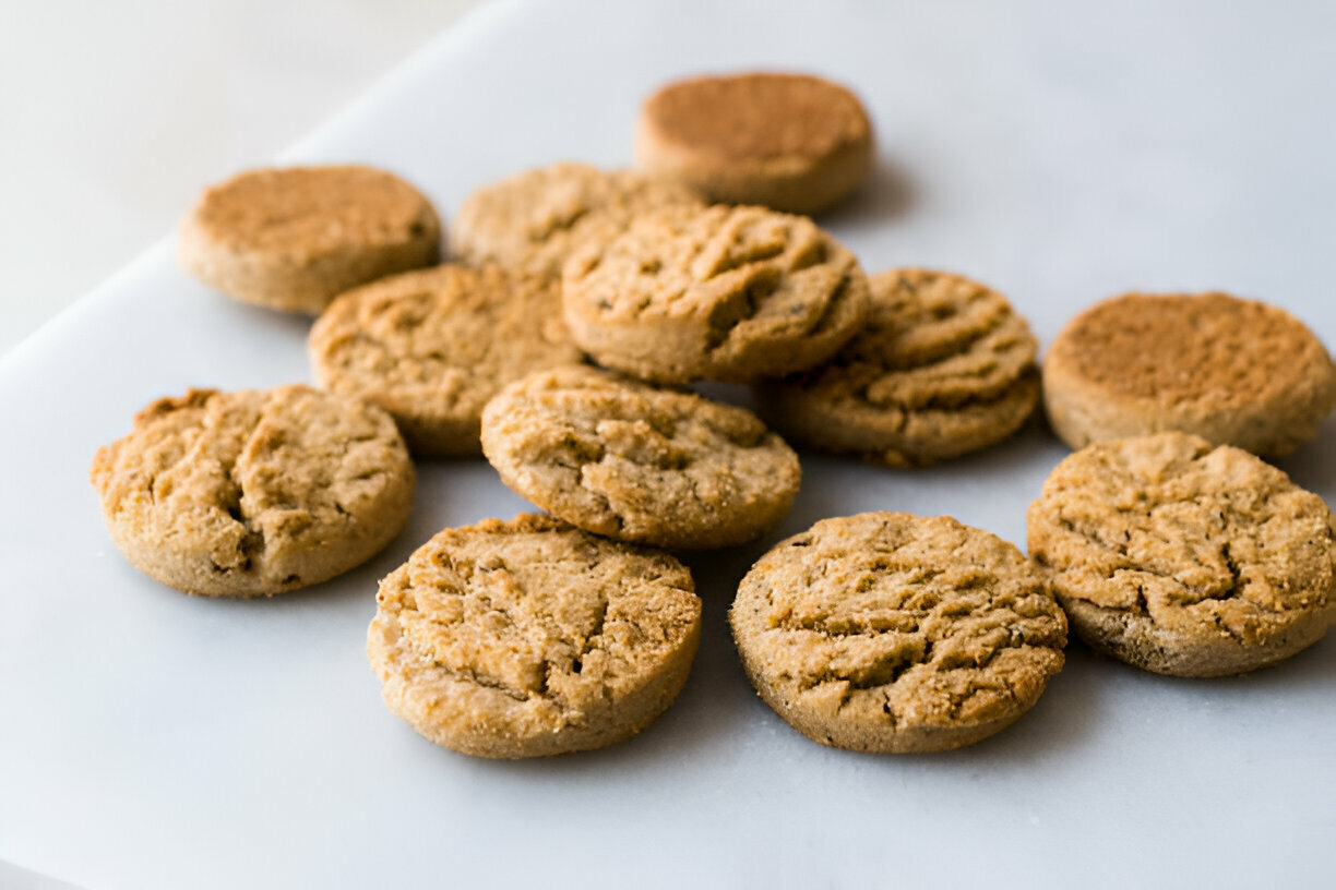 A collection of round, lightly golden cookies arranged on a white surface.