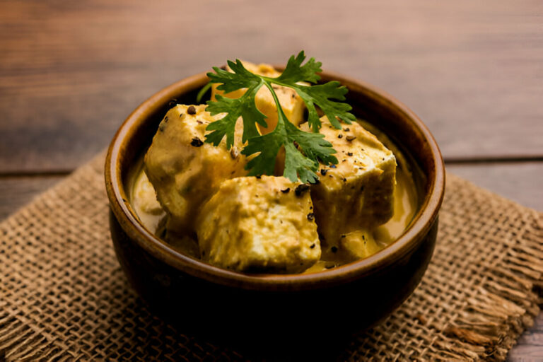 A bowl of creamy paneer curry garnished with fresh cilantro leaves.