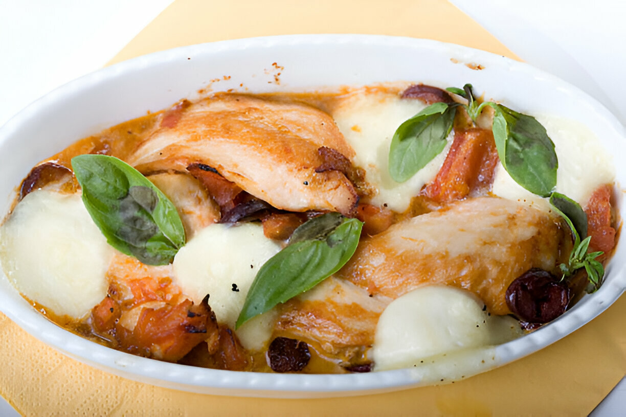 A delicious baked dish featuring chicken, melted cheese, and fresh basil leaves.