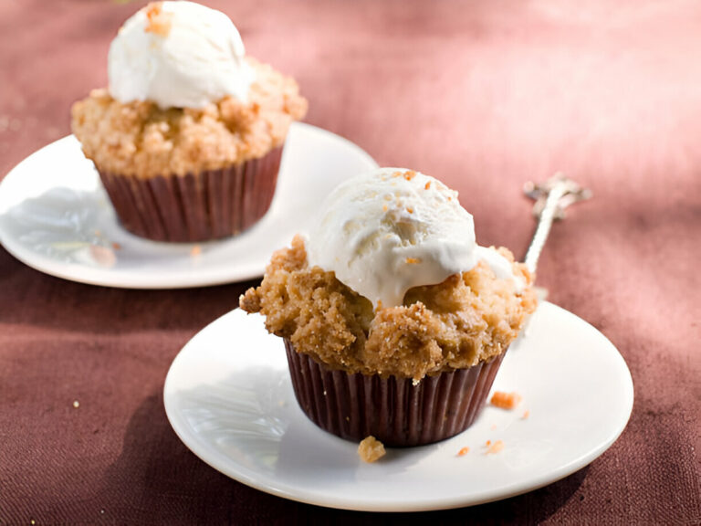 Two scrumptious cupcakes topped with vanilla ice cream, placed on white plates.