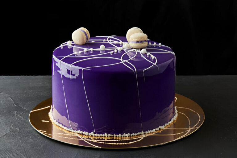 A beautifully designed purple cake with white accents and macarons on top, set against a black background.