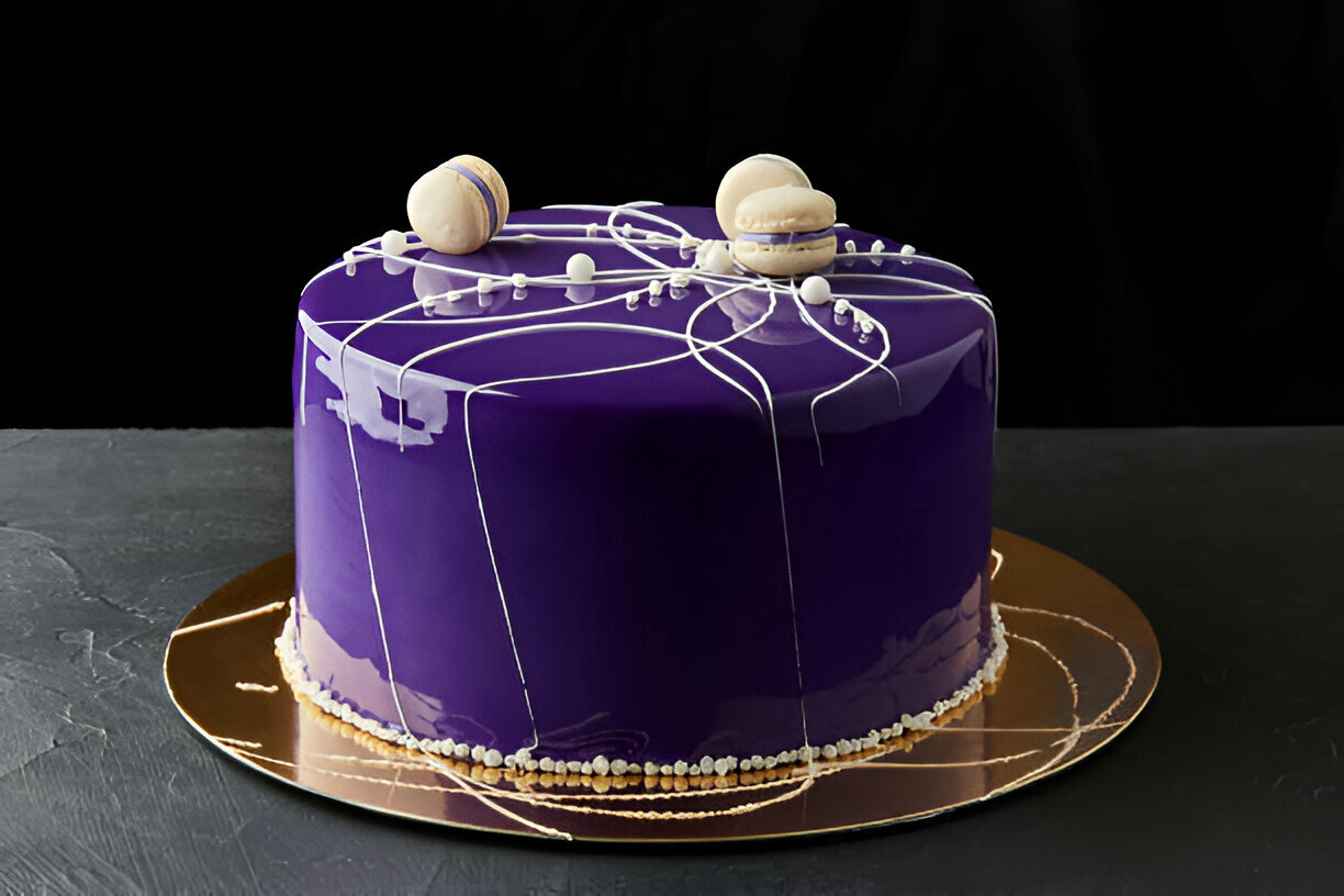 A beautifully designed purple cake with white accents and macarons on top, set against a black background.