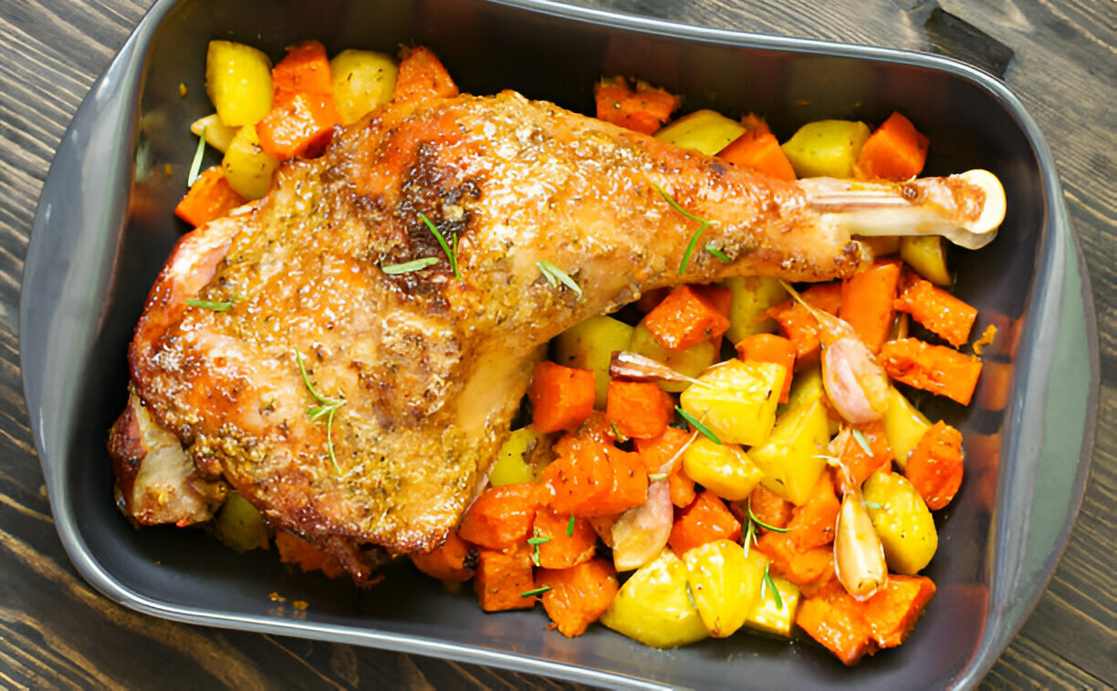 A succulent roasted turkey leg served with a colorful medley of roasted vegetables including carrots, potatoes, and shallots.