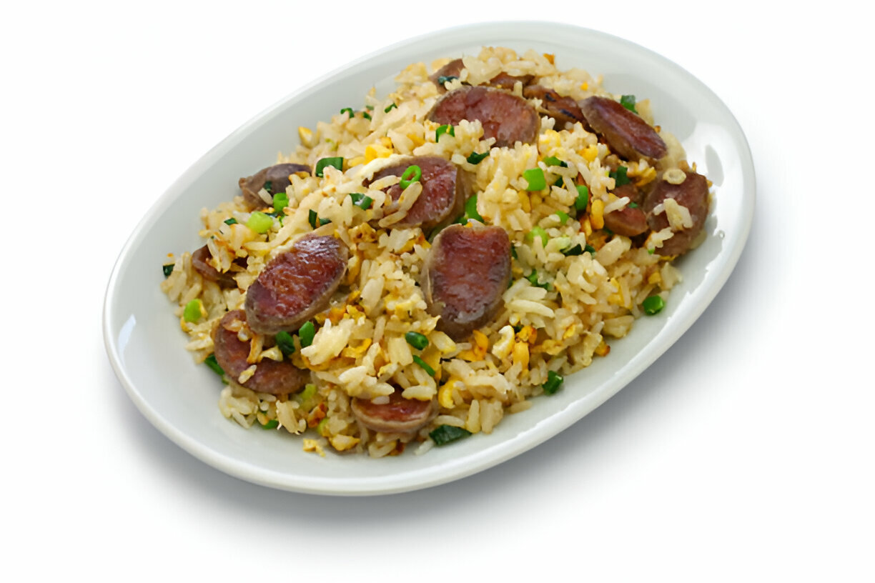 A plate of fried rice with slices of sausage and green onions