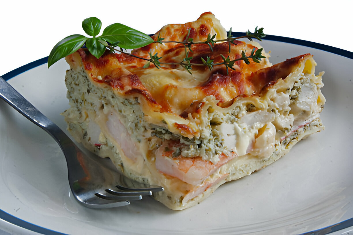 A delicious slice of lasagna topped with fresh basil and thyme, served on a plate with a fork.