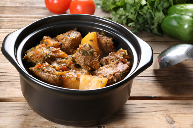 A hearty stew with chunks of meat and vegetables in a black pot on a wooden table.