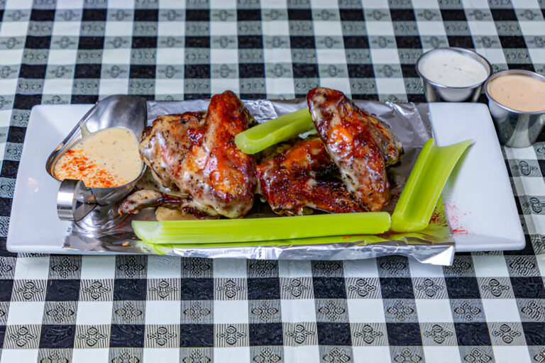 Delicious grilled chicken wings served with celery and dipping sauces on a silver platter