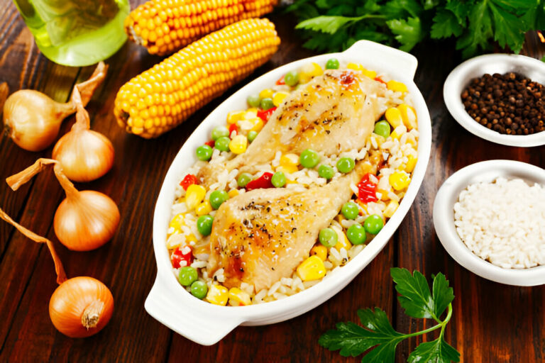 A delicious dish of baked chicken served with rice, vegetables, and spices on a wooden table.