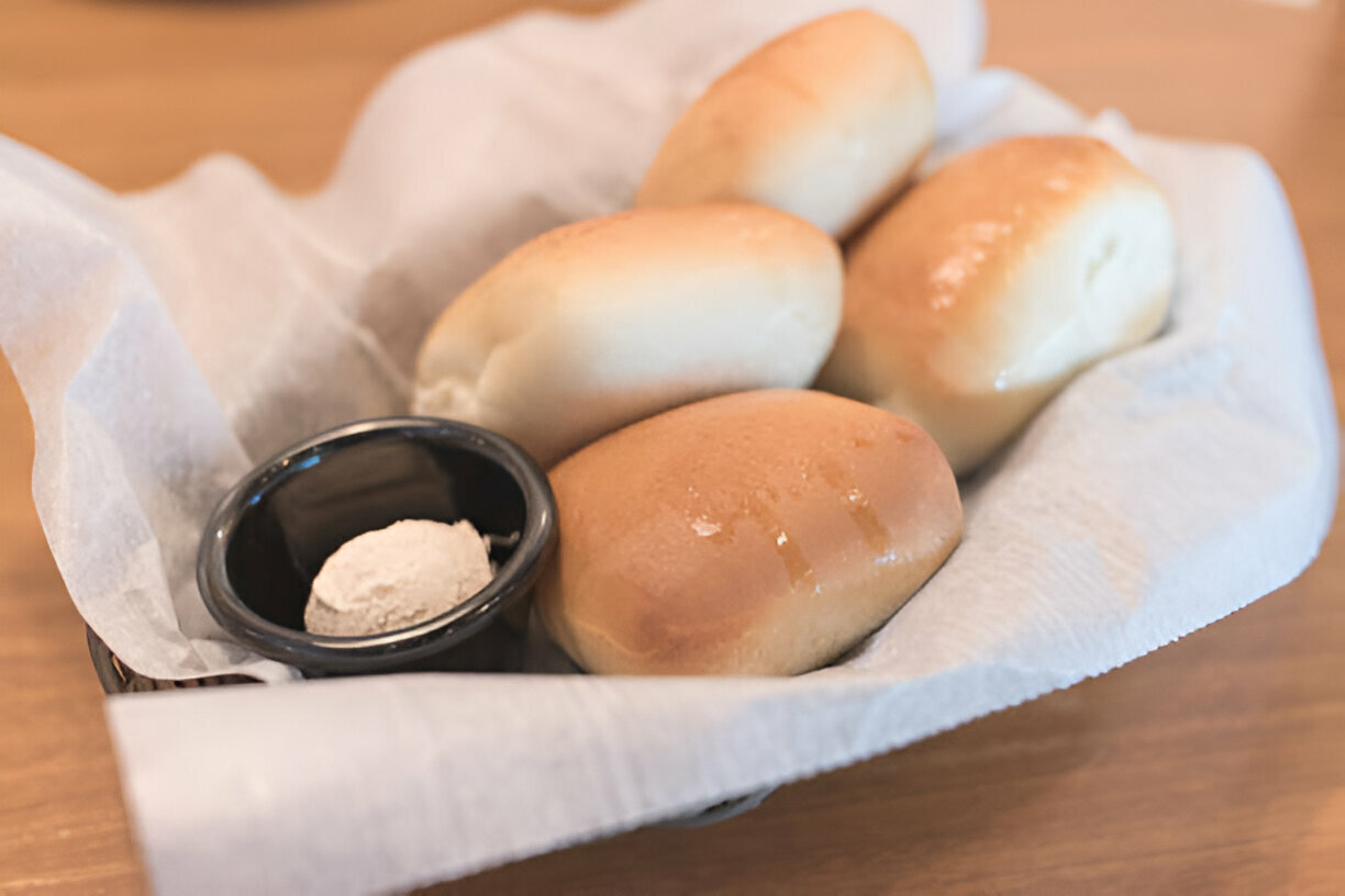 A basket of freshly baked rolls with a small dish of butter on the side.